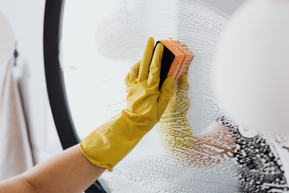 Reinigung einer Glasfläche mit Handschuh und Schwamm bei einer Endreinigung